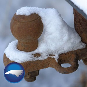 a rusty, snow-covered trailer hitch - with North Carolina icon